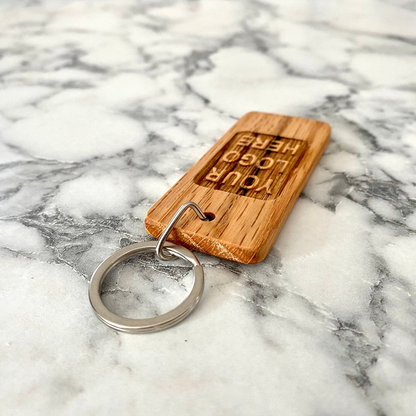 Angled view of custom engraved oak wood keychain with YOUR LOGO HERE | Mrs Gift
