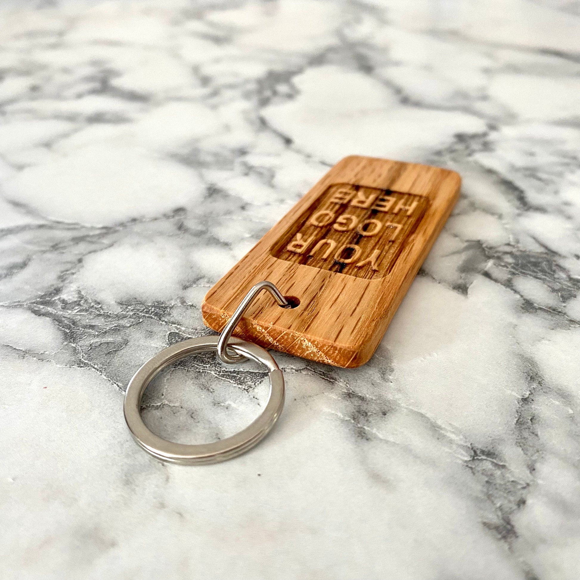 Angled view of custom engraved oak wood keychain with YOUR LOGO HERE | Mrs Gift