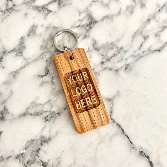 Flatlay of oak wood keychain engraved with YOUR LOGO HERE for corporate branding | Mrs Gift